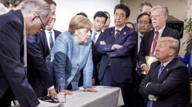 In this photo made available by the German Federal Government, German Chancellor Angela Merkel, center, speaks with U.S. President Donald Trump, seated at right, during the G7 Leaders Summit in La Malbaie, Quebec, Canada, on Saturday, June 9, 2018. (Jesco Denzel/German Federal Government via AP)