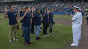 Capt. Joey Frantzen administers the oath of enlistment to Navy recruits in the Delayed Entry Program during Navy Night at Harbor Park Stadium.