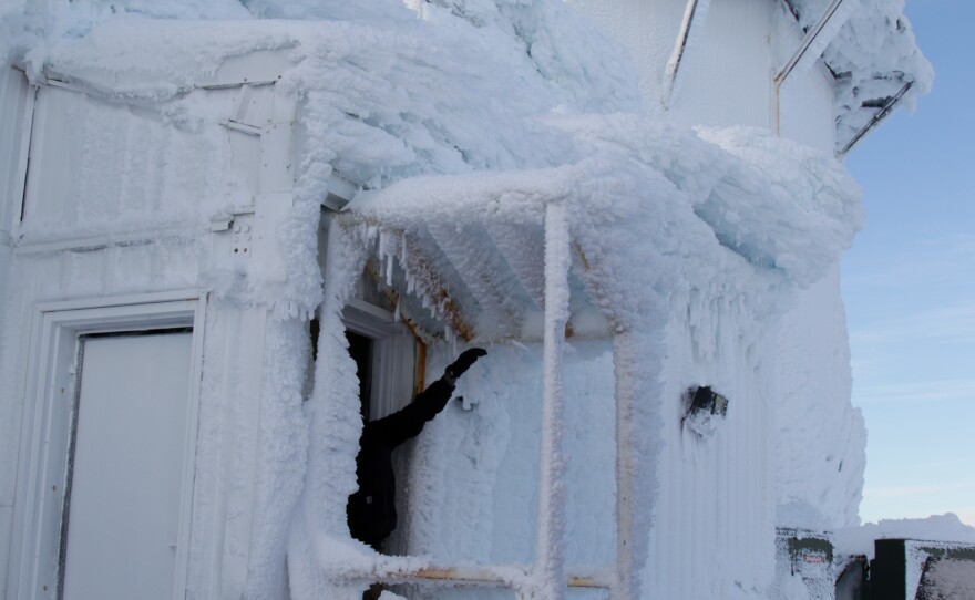 A contractor clears ice from the door of the long-range radar building at Tin City.