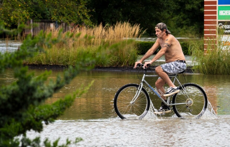 A cyclist makes his way through floodwaters Aug. 14, 2026, in Noblesville, Ind.