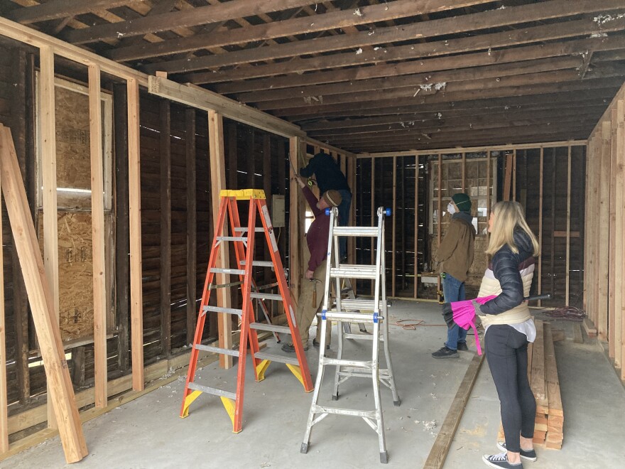 Amy Blansit, right, looks on at construction workers as they renovate a former 'long-term druggy house' into a garage for a Grant Beach home on March 21, 2023.