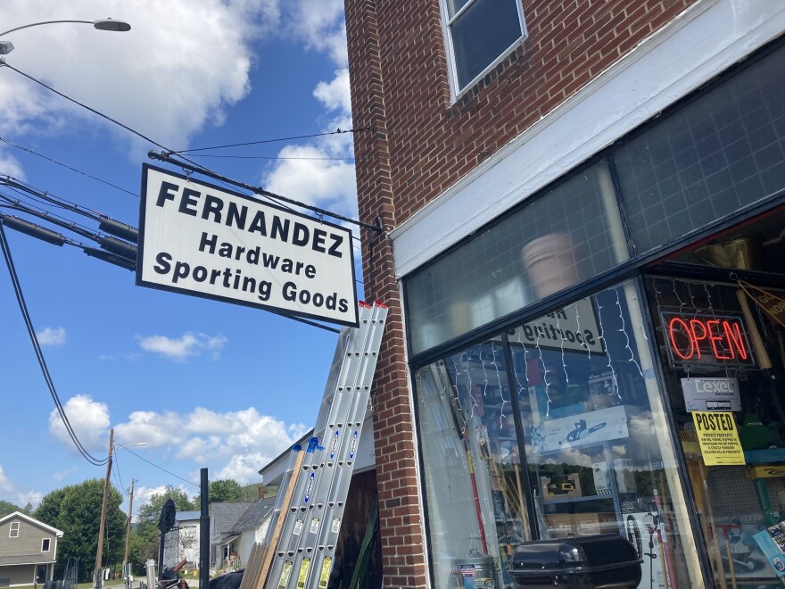 A black and white sign on a brick building reads "FERNANDEZ Hardware Sporting Goods"