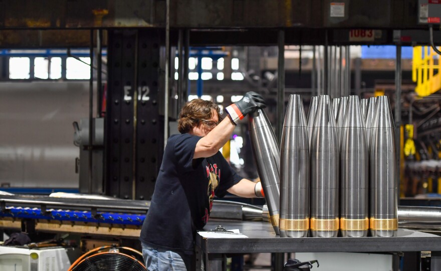 An employee at the Scranton Army Ammunition Plant moves an unpainted 155-milimeter artillery shell.