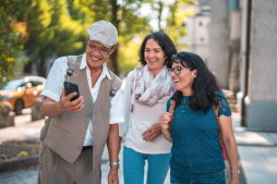 Active senior and mature friends using a smart phone outdoors. They are traveling and enjoying a fulfilling life.