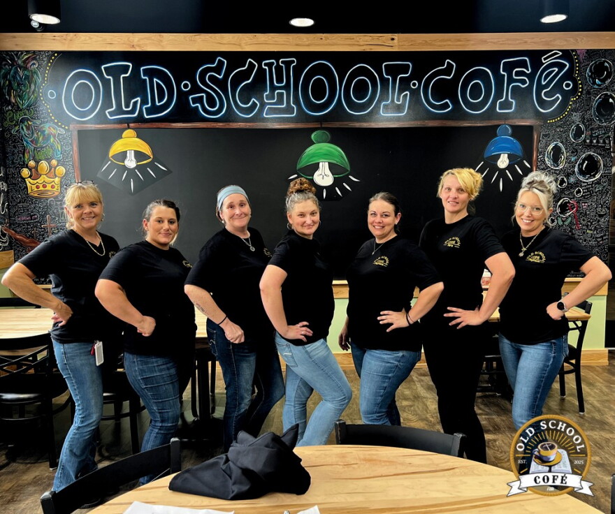Seven women in black shirts pose for a photo.