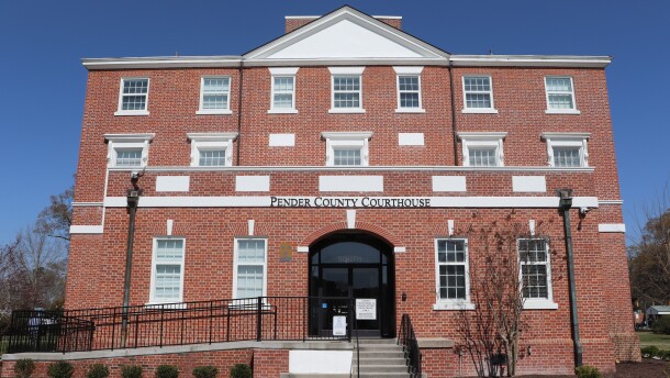 The Pender County Courthouse, a multi-story red brick building, photographed from the west lawn. 