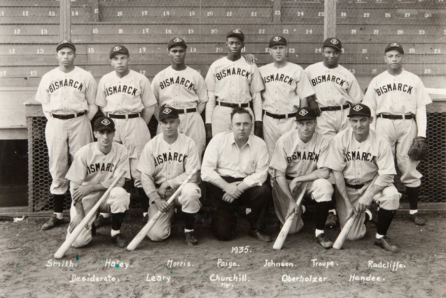 The 1935 baseball team from Bismarck, North Dakota, was a rarity because it included both Black and white players. The team won the first National Baseball Congress, led by future Hall of Famer Leroy “Satchel” Paige. He’s in the back row, directly behind team owner Neil Churchill, a local car dealer.