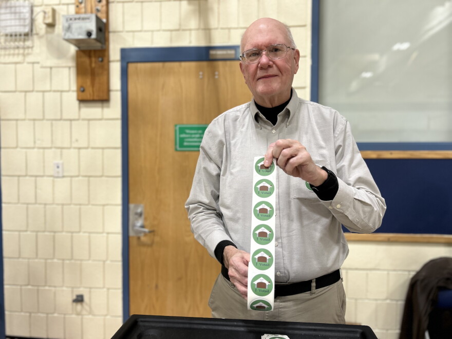 Plymouth election moderator Robert Clay holds up a roll of "I voted" stickers.