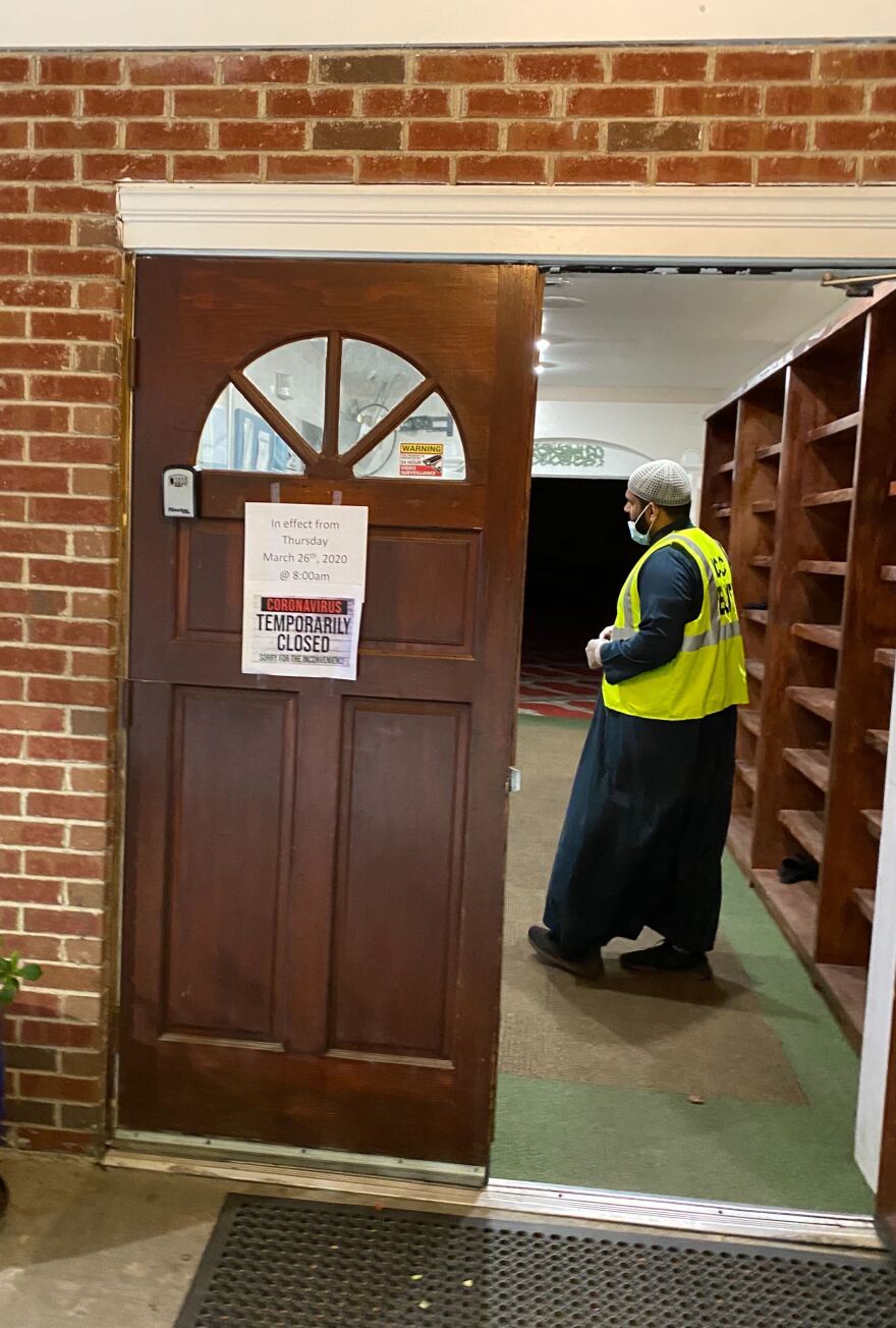 Imam Muhammad Khan stands inside the entrance of the Islamic Center of Charlotte, closed due to the coronavirus pandemic.