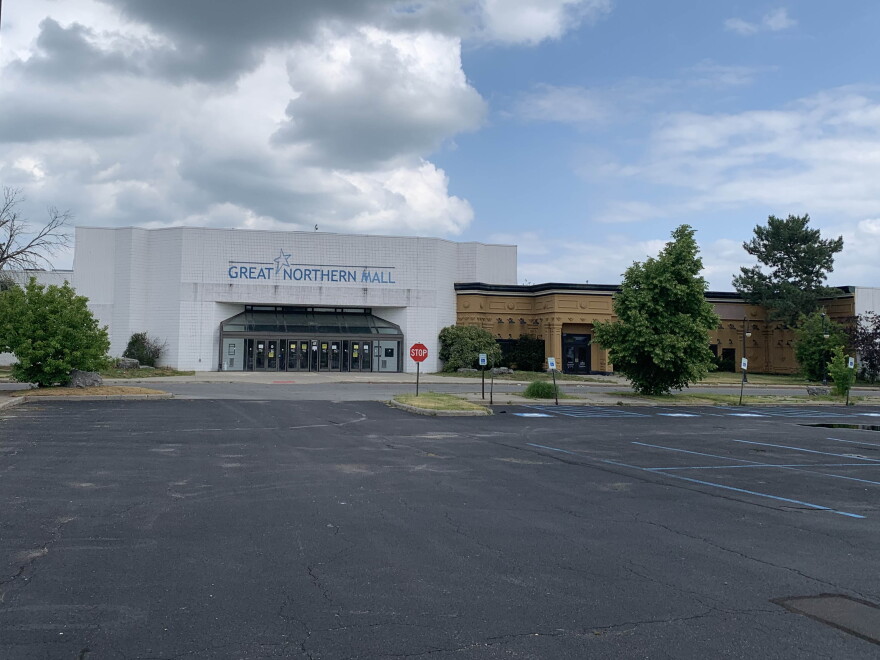 A dated mall in the background with an empty parking lot in the foreground.  