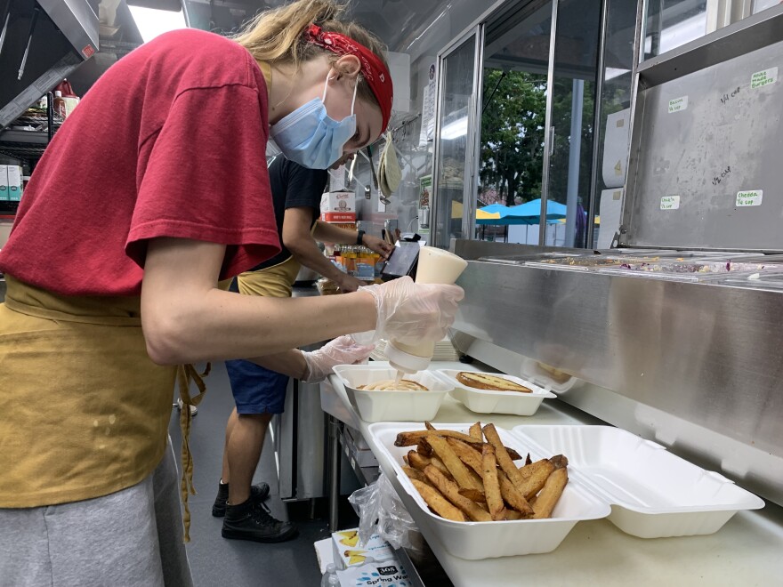 Abby Cochrane, a Plantology cook, crafts a vegan burger order. (Abigail Hasebroock/WUFT/News)