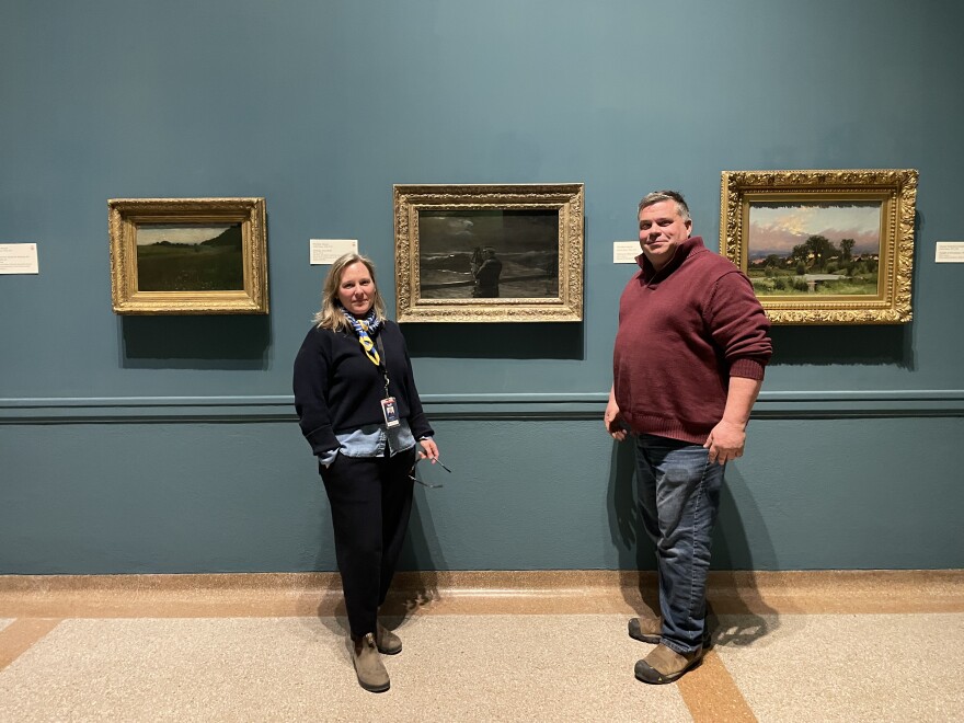 Erin Damon, Head of Collections, and Mike Brown, Director of Sustainability, at the Portland Museum of Art, standing with a painting by Winslow Homer.