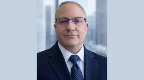 A head and upper chest photo of a white man in a dark suit and tie. He is new Bloomington Water Director Brett Lueschen.