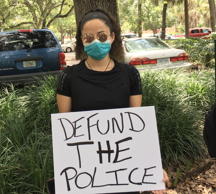 Samar Perez holds a defund the police sign