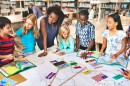 students and teacher stand around a table in a library