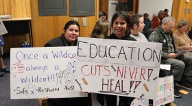 A mother and daughter hold signs at a Corvallis School Board meeting