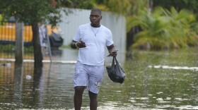 A man walks on a flooded street on his way to work, Thursday, June 13, 2024, in North Miami, Fla. A tropical disturbance has brought a rare flash flood emergency to much of southern Florida. Floridians prepared to weather more heavy rainfall on Thursday and Friday.