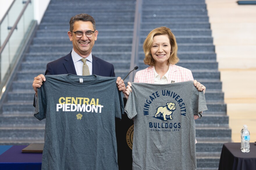 Wingate President Rhett Brown and CPCC President Kandi Deitemeyer display T-shirts from each other's schools Tuesday.