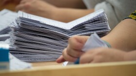 A person counting ballot papers at an election