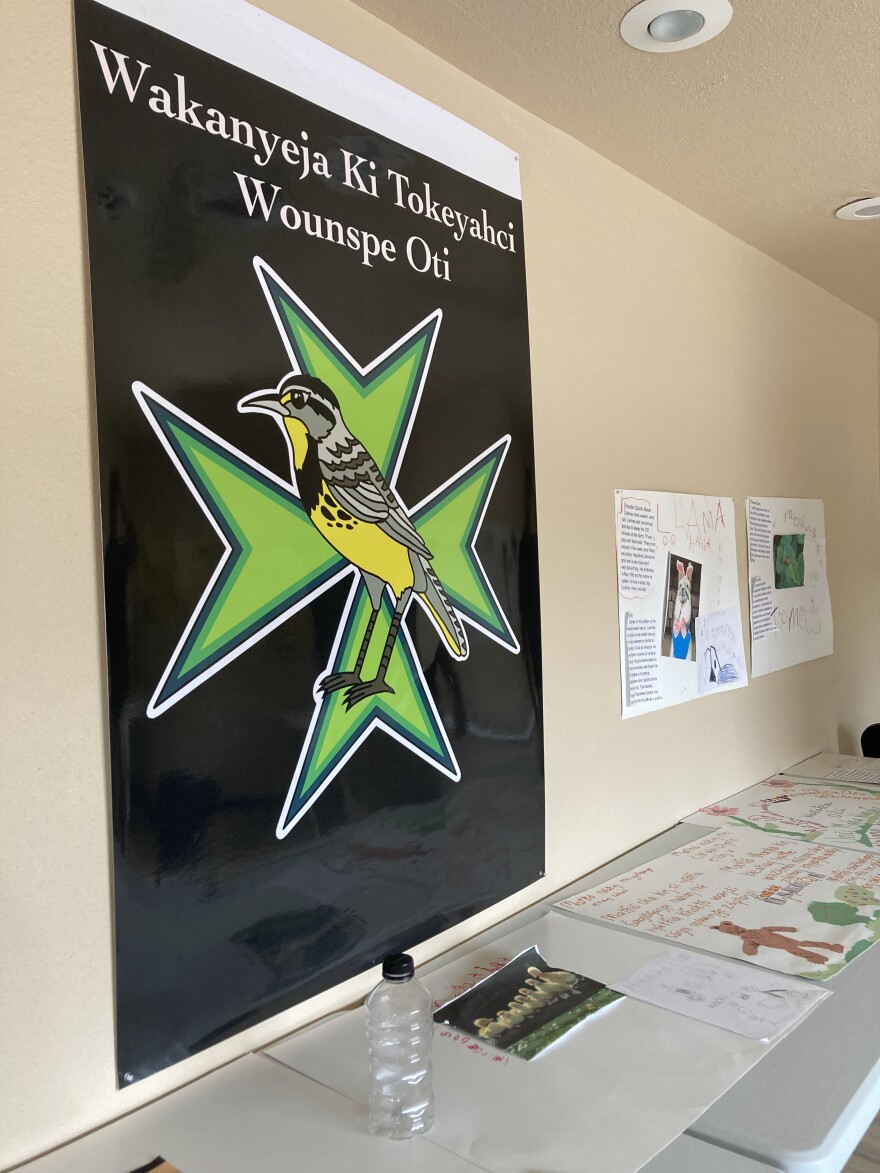 A poster of the official logo for Wakanyeja Tokeyahci Lakota Immersion School in Mission, South Dakota, along with Lakota language projects of some of the school's students.