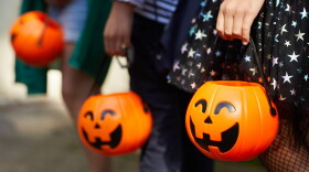 Close-up of children with pumpkins bags playing trick or treat outdoors