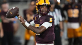 Football player in a maroon and gold uniform throws a football. 