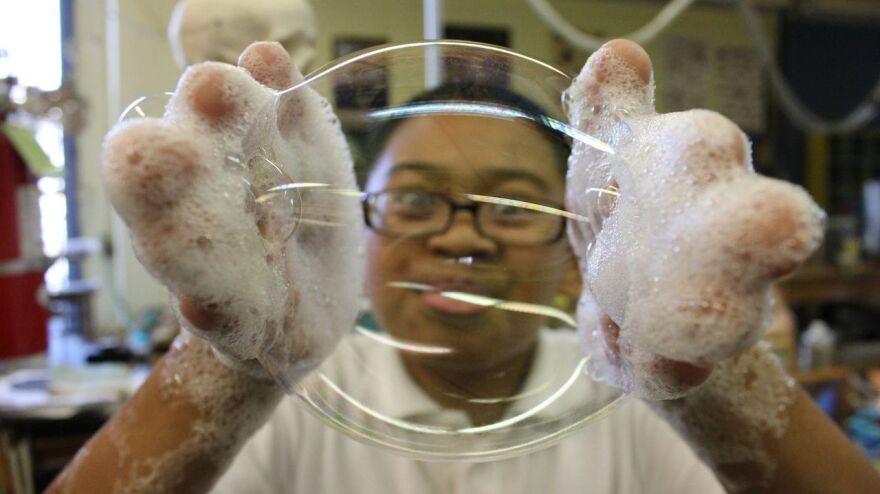 Hands-on science activities like making bubble mitts at the Mission Science Workshop teach students about things like surface tension.