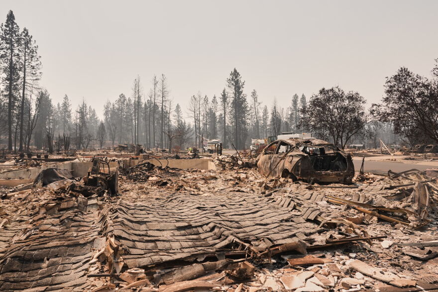Dozens of houses are seen destroyed in a residential neighborhood as crews begin to check the area after a wildfire hit the northern part of Spokane, Wash., Tuesday, Aug. 4, 2026. (AP Photo/Lindsey Wasson)
