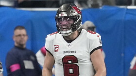 football player with white jerseys and pewter helmet celebrate on the field.