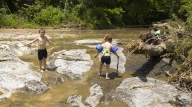 Children play in a small tributary of the Illinois River near Tahlequah, Okla., in May 2015. 
