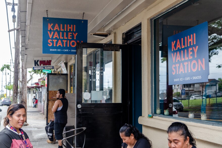 Residents wait outside the Kalihi Valley Station as their phones charge from a portable battery, located inside the station. (August 17, 2026)