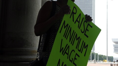 Wendy Brown of Schenectady, N.Y., holds a sign before an Occupy Albany rally pushing for a raise in the state's minimum wage at the Capitol in Albany N.Y., on Tuesday, May 29, 2012.