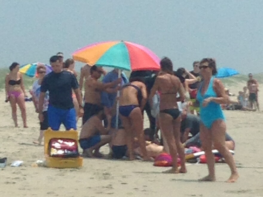 People surround and attend to a 68-year-old man who was bitten by a shark in waist-deep water off Ocracoke Island, N.C., on July 1. The man suffered wounds to his rib cage, lower leg, hip and both hands as he tried to fight off the shark.
