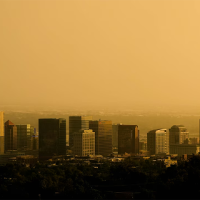 The Salt Lake City skyline veiled in smoke. The air appears yellow as the sun sets. 