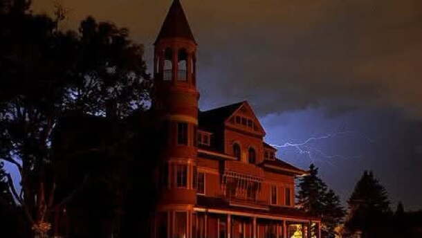 Mansion with a conical tower against a stormy night sky