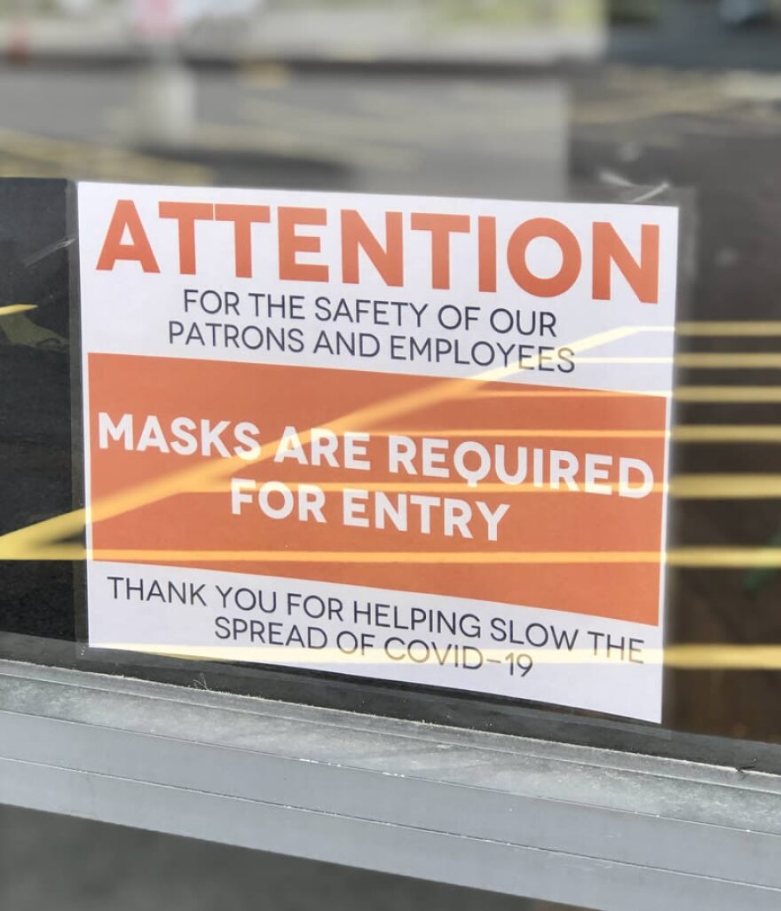 Sign on a business door that says 'Attention: for the safety of our patrons and employees, masks are required for entry. Thank you for helpping slow the spread of COVID-19.'