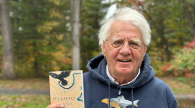 Author Michael Delp poses with a copy of his new book, "Of Blood and Rivers," a collection of elegies about grief and loss. (Photo: Ed Ronco/IPR News)