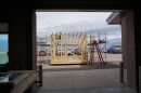 Two students work on the top of a framed, wooden structure outside.