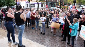 Ashley Theissen (left, holding microphone) addresses the crowd of around a hundred gathered at the Hamilton County Courthouse Thursday to protest Judge Brett Kavanaugh's nomination to the U.S. Supreme Court.