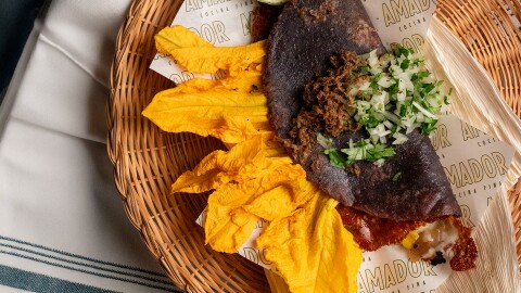 A taco on a bed of yellow leaves with a cilantro topping