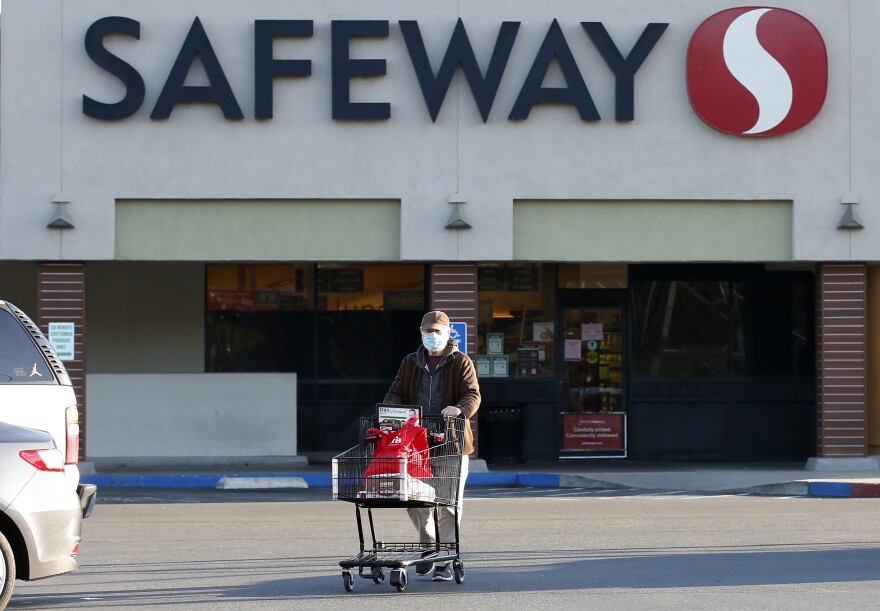 Wearing a mask for protection, Henry Powell, heads to his car after shopping at a Safeway store in Sacramento, Calif., Thursday, March 19. Safeway is among the stores that are offering special shopping hours for seniors amid the coronavirus outbreak.