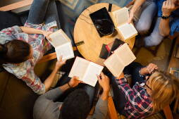 Diverse group of friends discussing a book in library. Directly above.