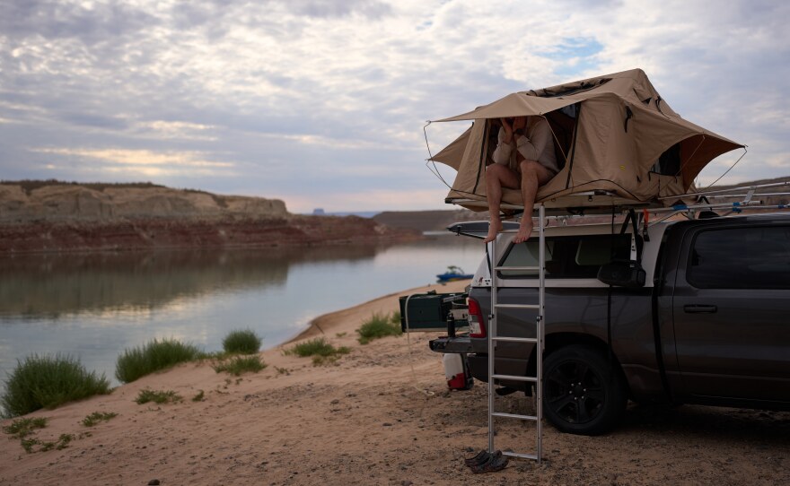 Mark Budzko rubs his eyes as he wakes up while camping beside Lake Powell at the Glen Canyon National Recreation Area, Wednesday, July 15, 2026, near Big Water, Utah. (AP Photo/John Locher)