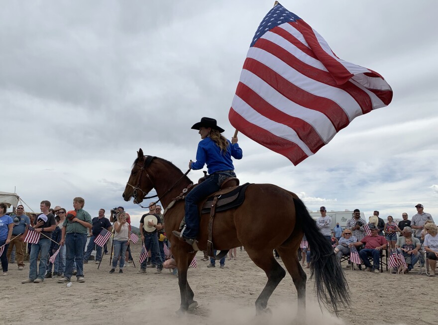 A member of the Klamath Falls Great Northwest Pro Rodeo flag team presents the colors for the crowd to sing the national anthem.