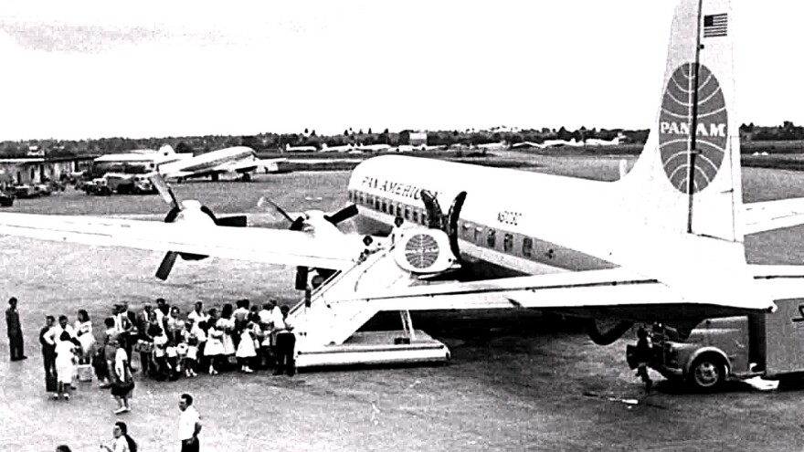 group in BW image gather to get on a Pan Am plane in the 1960s 