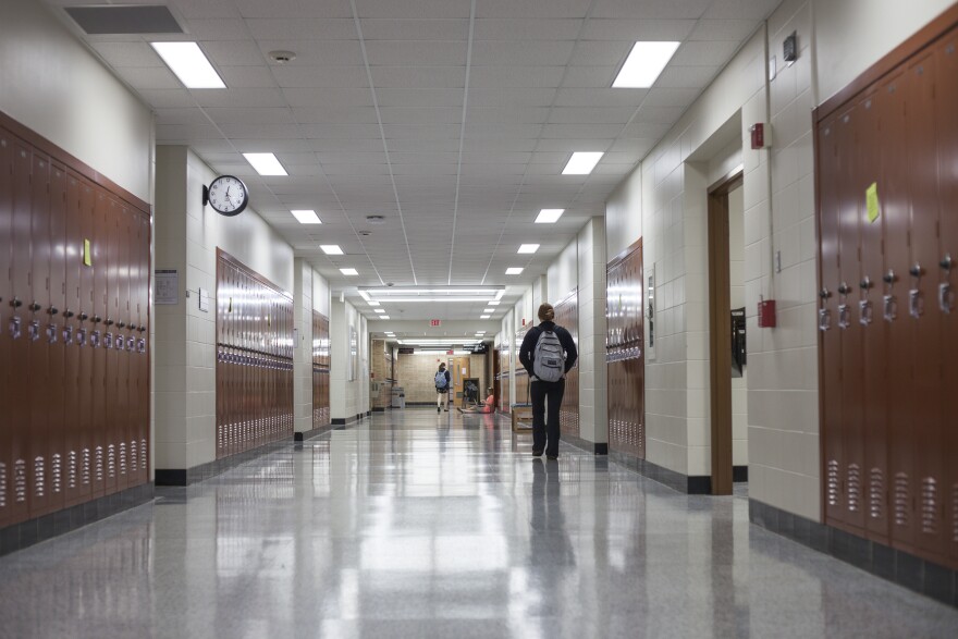 A student walks down a school hallway lined with lockers.