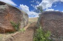Two large rocks frame a dirt trail. 