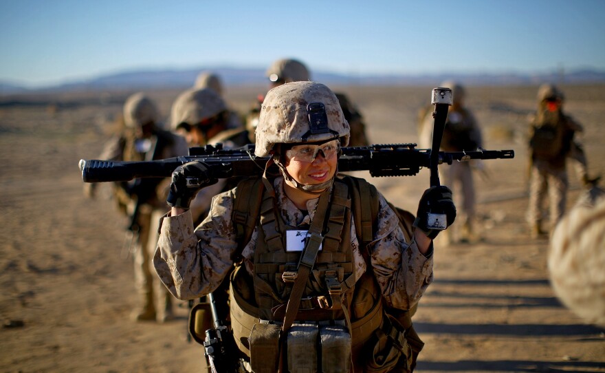 Sgt. Courtney White carries her machine gun before a live-fire exercise. 