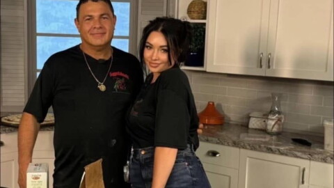 Frank and Alyssa Cappello are posing for a photo in front of a kitchen table. 
