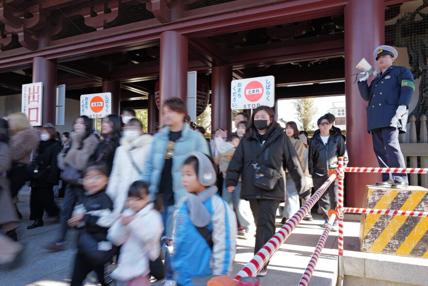 A police officer controls visitors to walk slowly as they move to the main hall to pray for good luck during their "hatsumode," or first visit of the year to a shrine or temple, at Kawasaki Daishi temple Saturday, Jan. 3, 2026, in Kawasaki near Tokyo.
